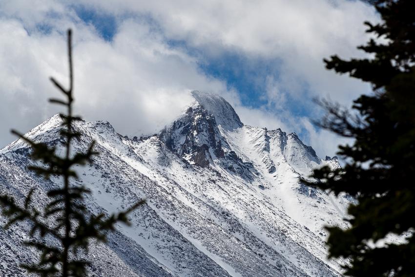 Longs Peak. 200mm, f/8.0, 1/1600s, ISO 100 Snow-covered mountain peak framed by evergreen trees