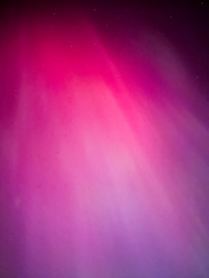 Purple aurora borealis with stars above